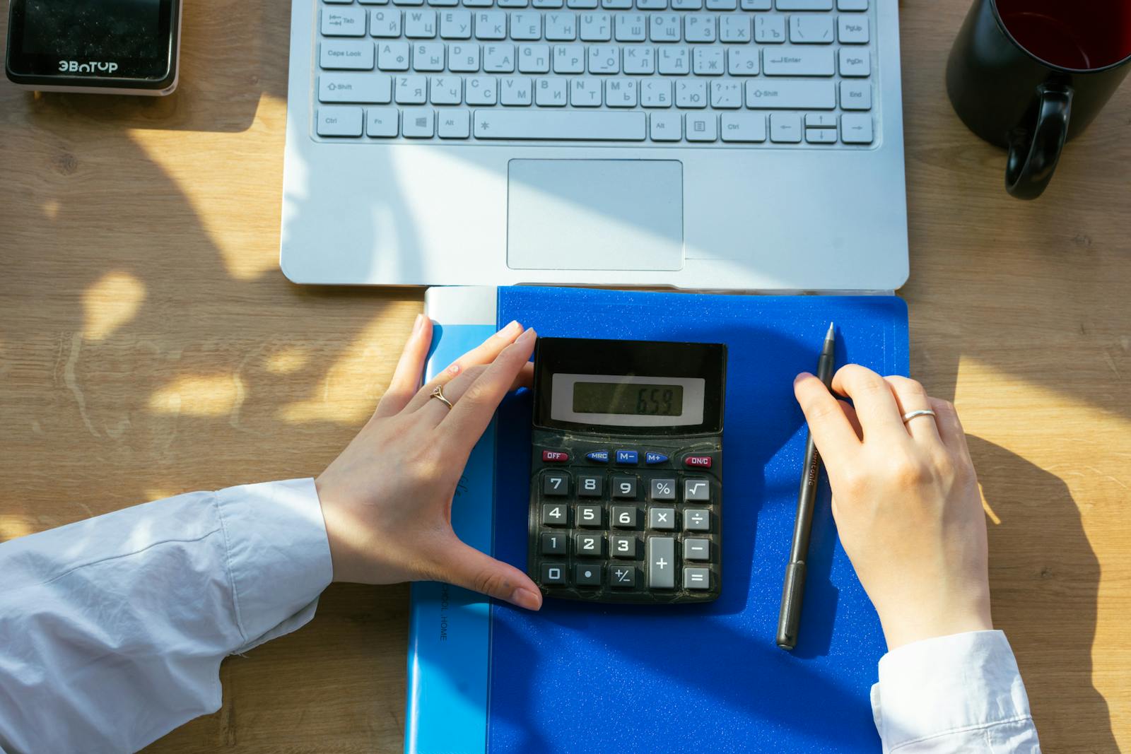 Accountant working on AutoCount on a desk with laptop and calculator